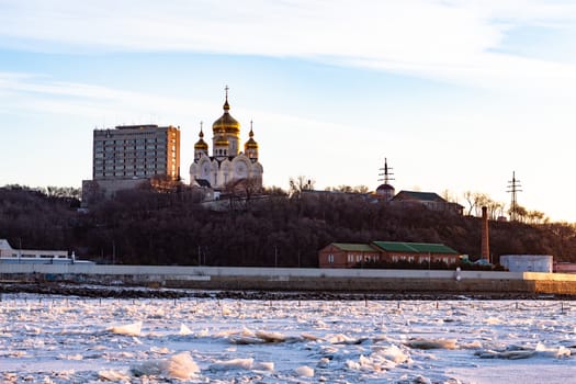 View of the city of Khabarovsk from the middle of the frozen Amur river. Factories on the horizon.