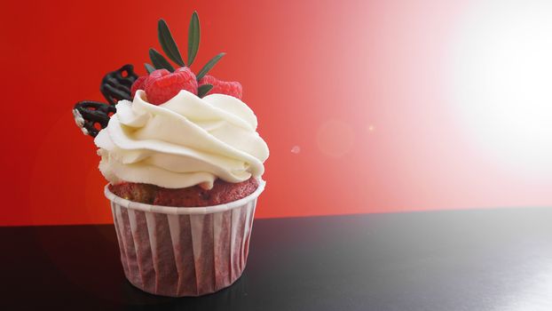 Delicious raspberry cupcakes on dark black and red background - Handmade Sweet dessert, cupcake with butter cream and raspberry