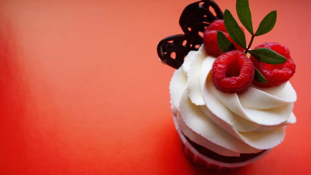 Handmade Sweet dessert, cupcake with butter cream and raspberry on red background