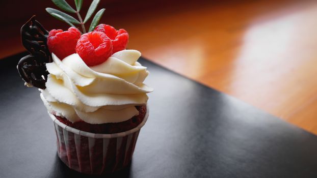 Delicious raspberry cupcakes on dark background - Handmade Sweet dessert, cupcake with butter cream and raspberry