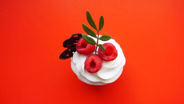 Handmade Sweet dessert, cupcake with butter cream and raspberry on red background