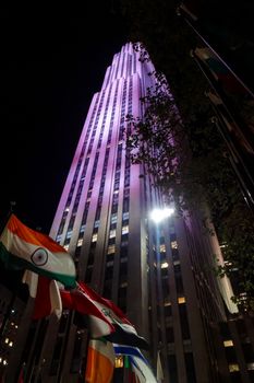Flags of different nations in front of Rockefeller Center at night