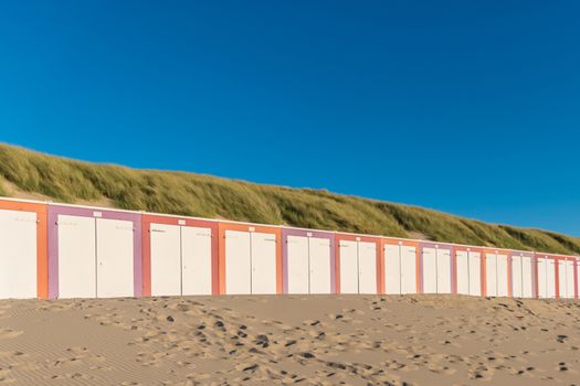 Colorful sheds at the beach in front dunes during sunset
