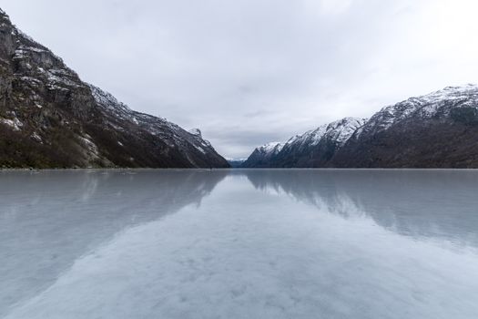 Hardanger fjord frozen smooth in winter with sheds Norway