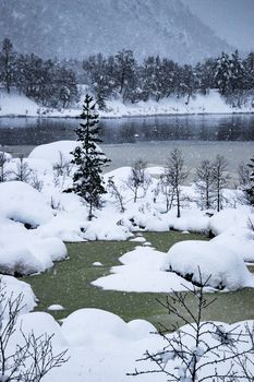 Lake half frozen in winter snowing