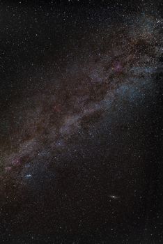 Center of milky way in night sky with red nebulas and andromeda