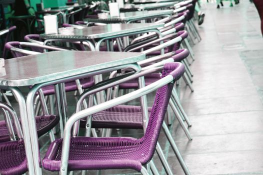 Empty European street cafe with purple chairs and tables, selective focus.