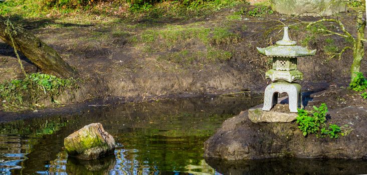 Water pond in a japanese garden with a tower sculpture, Asian garden background