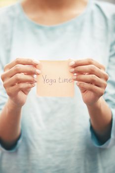 Woman holds adhesive note with Yoga time text