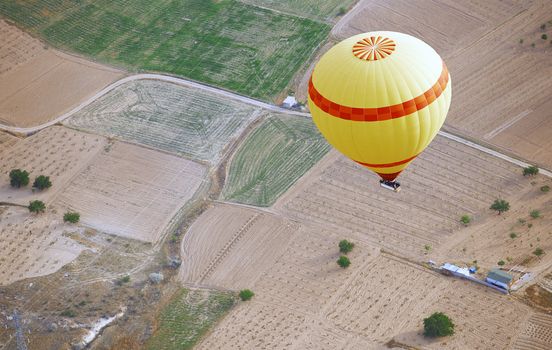 Yellow hot air balloon flying over the land