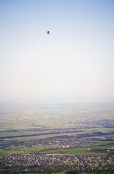 Hot air balloon above the green field and villages