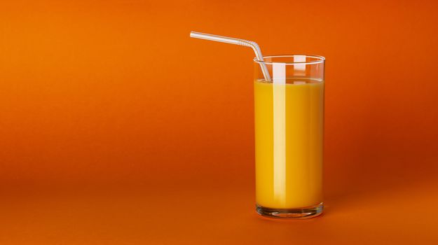 Glass of orange juice with straw isolated on colour background with copy space. Fresh citrus juice, orange cocktail, healthy drink concept, close-up