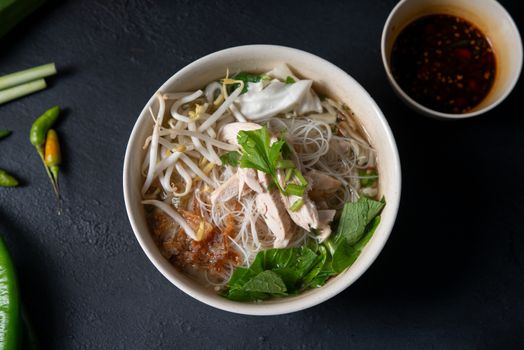 Asian rice noodles soup with vegetables and chicken in bowl. Top view flat lay.