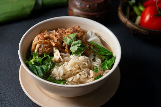 Asian ramen noodles soup and chicken in bowl on dark background. 