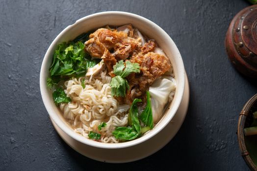 Asian ramen noodles soup and chicken in bowl on dark background. Top view flat lay.