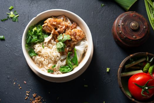 Asian ramen noodles soup with vegetables and chicken in bowl on wooden background. Top view flat lay.