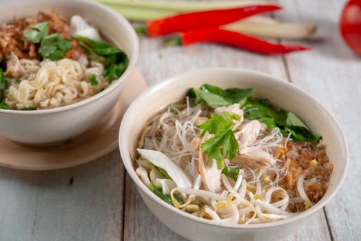 Asian soup noodles with chicken in bowl on wooden table. 