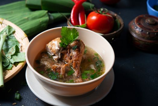 Asian style chicken soup in bowl, dark background.