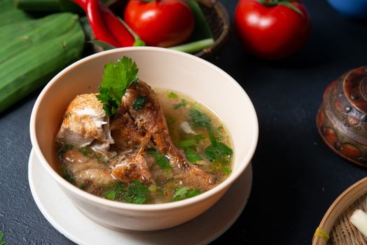 Asian style chicken soup in bowl, dark background.