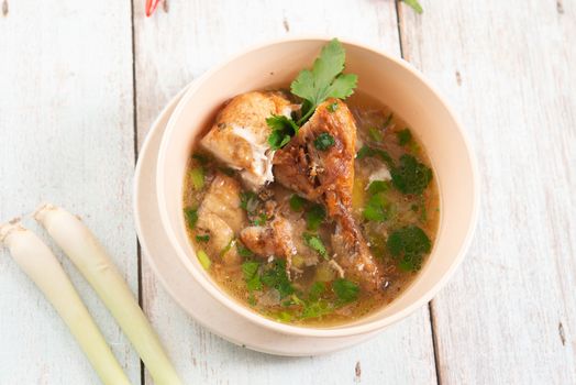 Asian style chicken soup in bowl, wooden background. Top view flat lay.