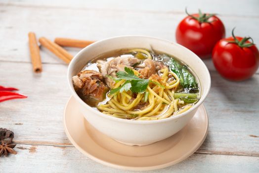 Asian soup noodles and chicken in bowl on wooden background. 