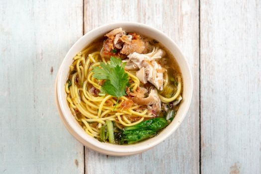 Asian soup noodles and chicken in bowl on wooden background. Top view flat lay.