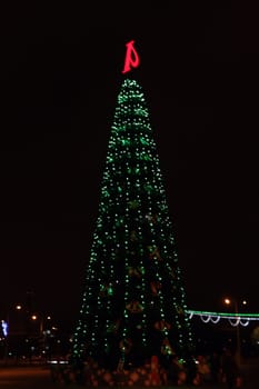 Christmas tree with lights on, in front of a city landscape at night