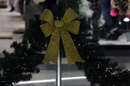 Yellow shiny bow and Christmas tree branch lies on gray background