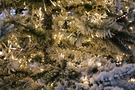 Christmas background - baubles and spruce branches. On the Christmas tree with glittering lights and artificial cotton wool. Christmas decorations, winter concept