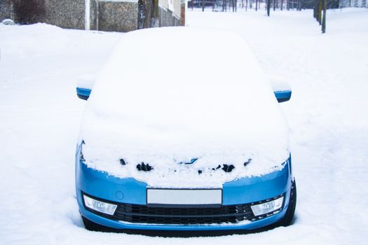 Frozen car covered snow at winter day, view front window windshield and hood on snowy background