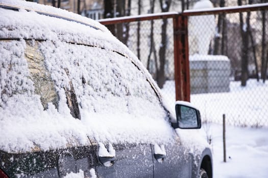 Snow covered ows of cars in the parking lot. Urban scene, snowstorm. Clean automobile from the snow