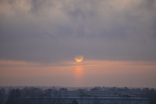 Winter dawn and the frosty fog. The sun rises over a small town