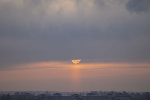 Winter dawn and the frosty fog. The sun rises over a small town