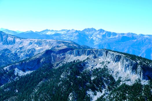 View from the top of the mountain or Olympus to the peaks on the background of clouds and blue sky.