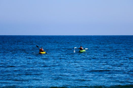 A pair of canoes in the Pacific. People kayak in the ocean