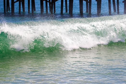 Waves break about the pier pile. USA