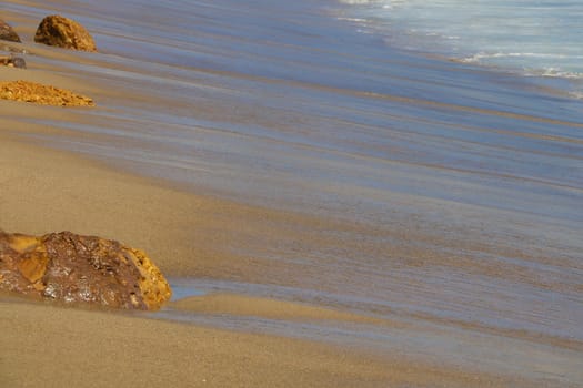 Coast of the Pacific Ocean with traces of waves with stones