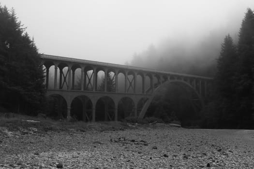 Old bridge in the fog on the coast of the Pacific Ocean black and white photo.