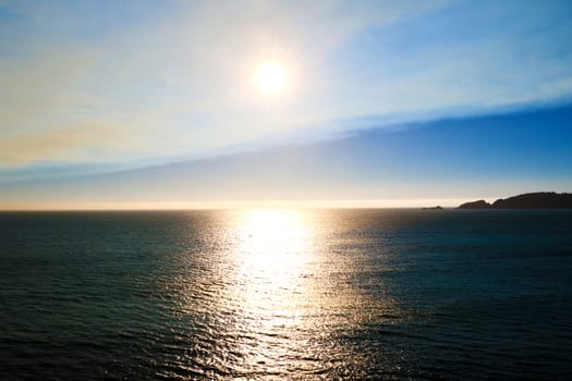 View of the beautiful sky and bright sun with reflection in the ocean.