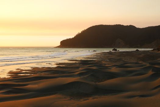 Warm sunset over the Pacific Ocean and the beach, a popular spot for surfers.