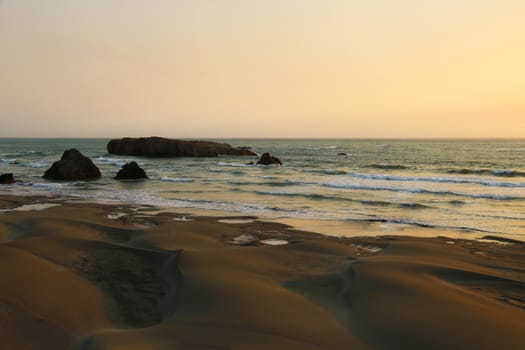 Sandy beach of the Pacific coast with rocks.