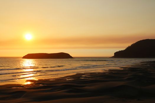 Beautiful sandy beach on the Pacific Ocean during a bright sunset.