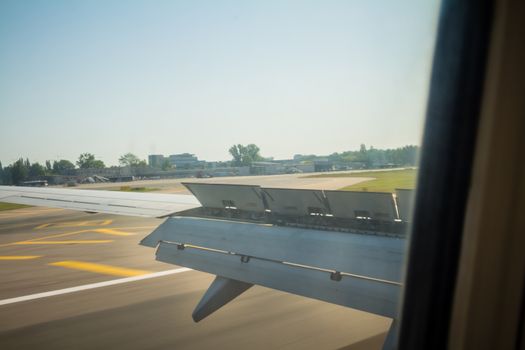Airplane wing during landing with flaps down on the runway.