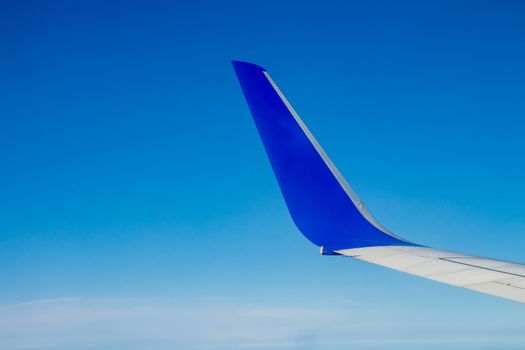 Airplane wing on the blue sky with clouds.