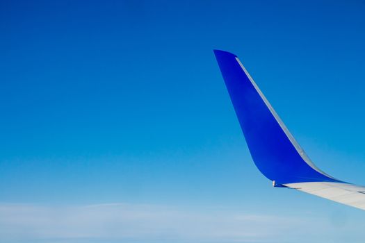 Airplane wing on the blue sky with clouds.