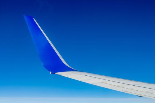 Airplane wing on the blue sky with clouds.
