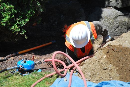 Utility worker repairing a broken water pipe underground.