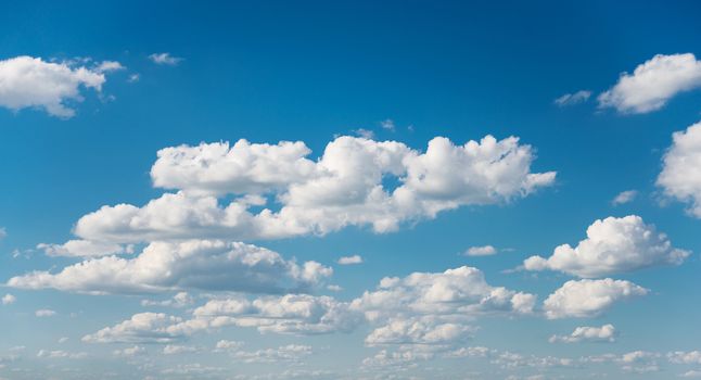 Vast blue summer sky with fluffy white cumulus clouds