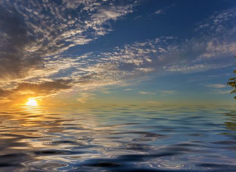 Beautiful sea landscape with dramatic sky with clouds and sun reflected in a water surface with small waves