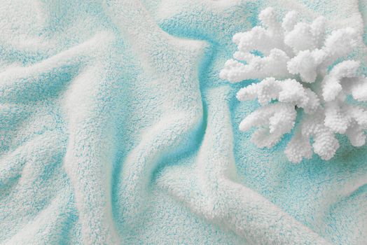 Beautiful white sea coral on the background of cotton terry blue towel, crumpled by waves